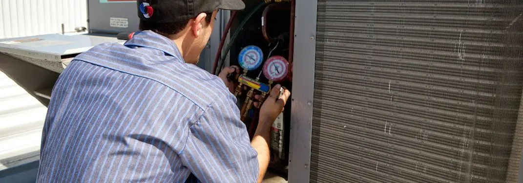 HVAC technician servicing a condenser unit in Winslow